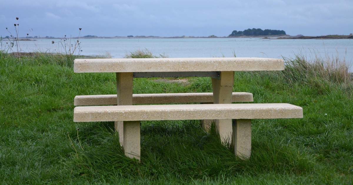 table pique nique en béton installée dans l'herbe